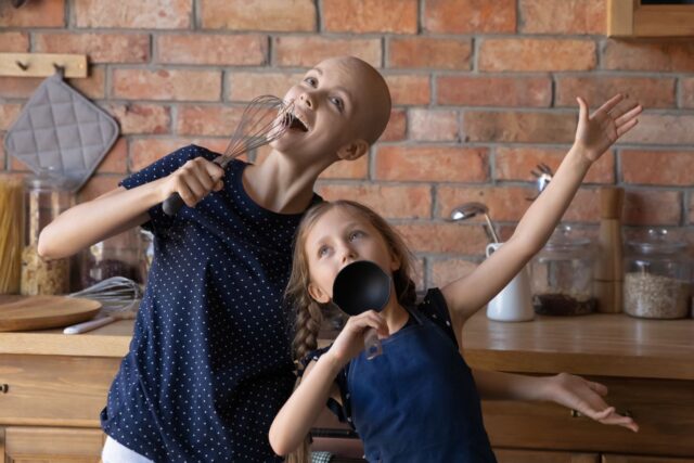 Cancer Survivor and Daughter Singing in a Kitchen