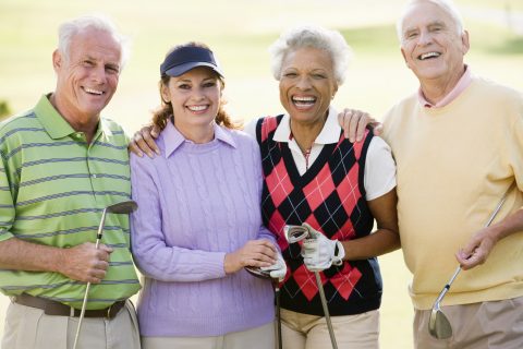 Four people smiling holding golf clubs